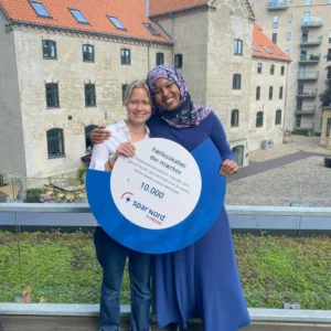 Asta og Fatima holder et donations-skilt fra Spar Nord Fonden