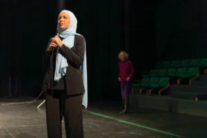 En kvinde med hijab taler alene på en scene